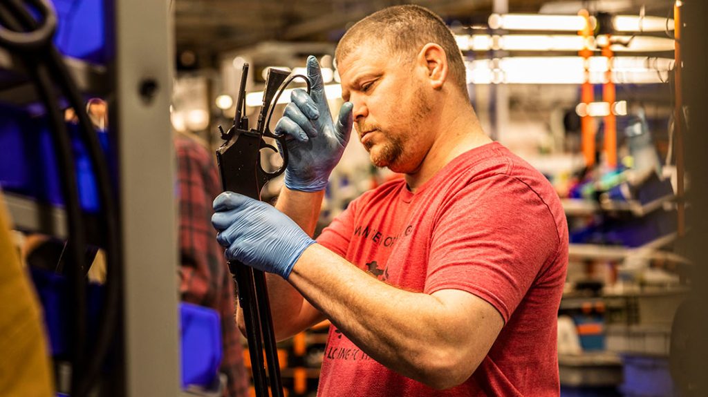 An employee assembles a lever-action rifle.