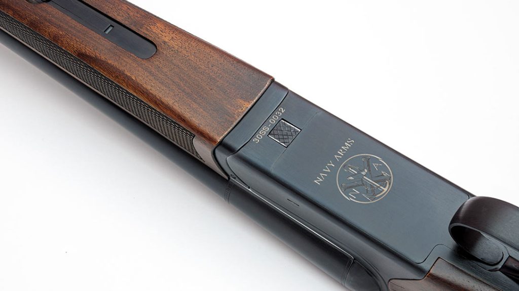 The scattergun has a checkered splintertype forend held to the barrels by a Deeley forend release. Note the Navy Arms logo laser-etched in the receiver of the Coach Gun.