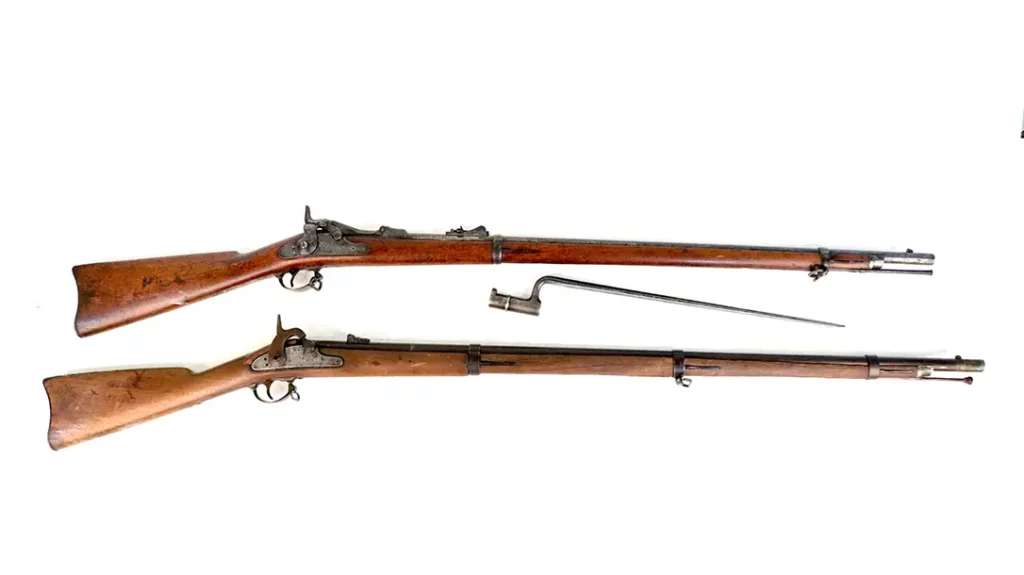 The Civil War-era Springfield rifle (bottom as represented by an M1864) served as the foundation for the Allin Trapdoor conversion.